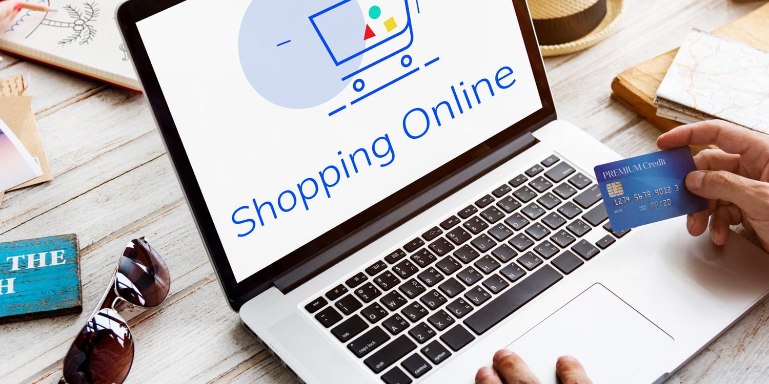 Compuradora con imagen de un carrito de e-commerce y una tarjeta de crédito en la mano