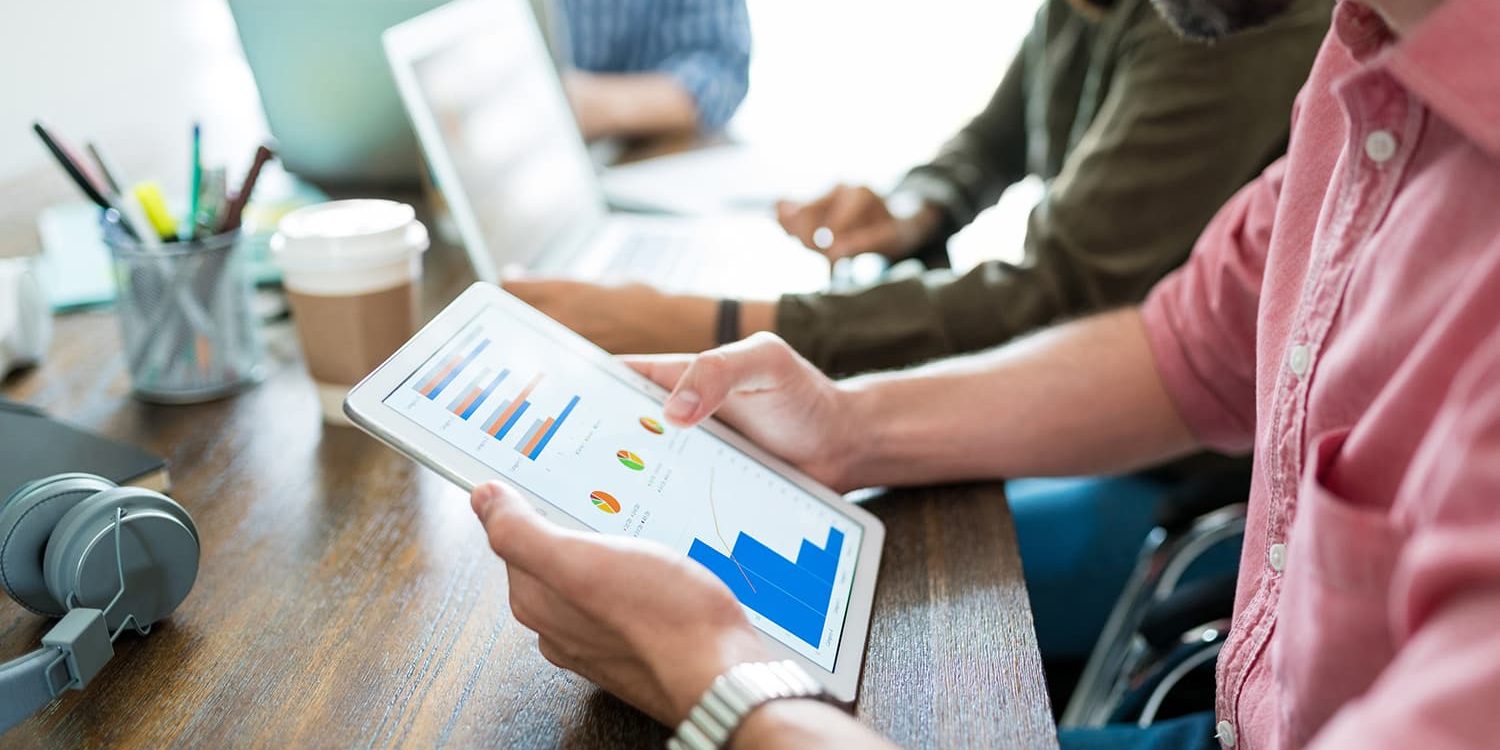 businessman-examining-graphs-digital-tablet-while-planning-with-coworkers-desk-office (1) Business team reviewing growth charts on a tablet