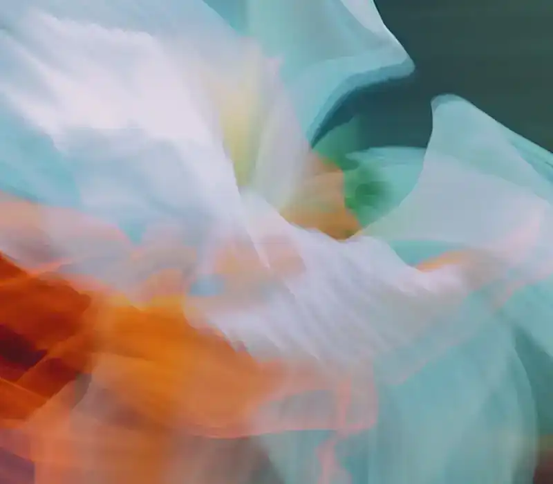 White and turquoise fabric in motion over a flash of orange